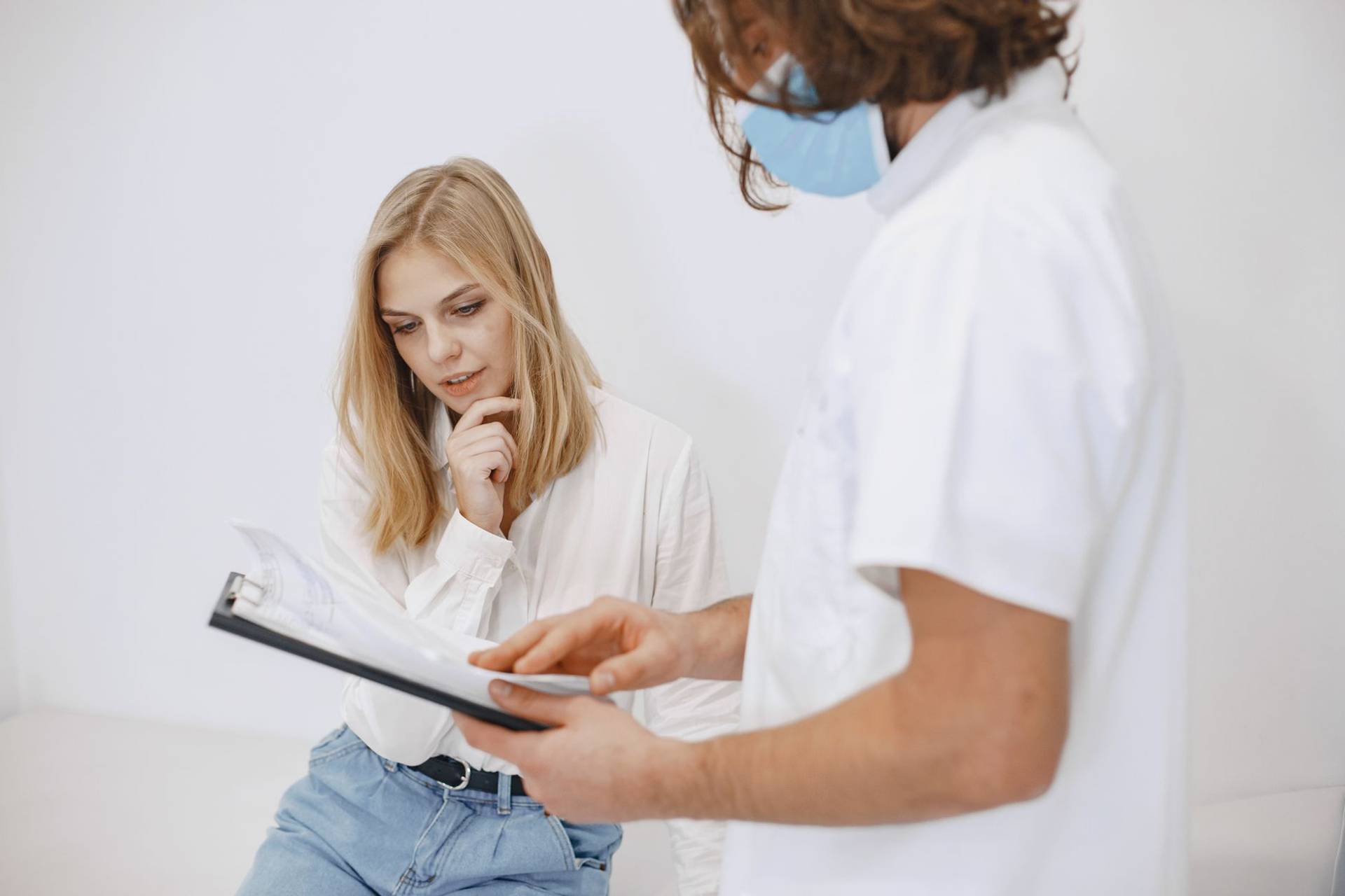 Un médecin en masque facial discute du diagnostic avec un patient dans un cadre clinique