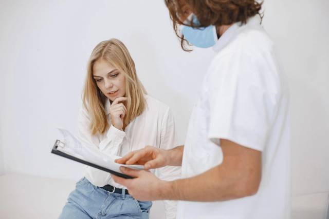 Un médecin en masque facial discute du diagnostic avec un patient dans un cadre clinique