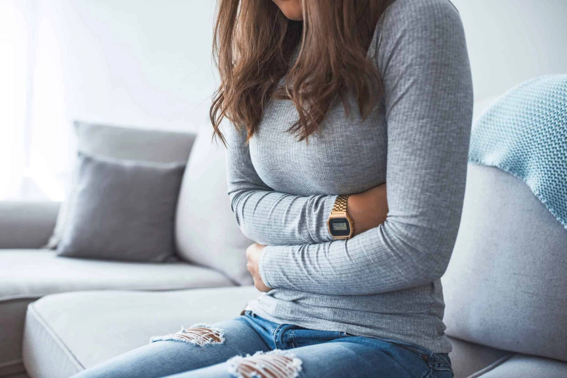 Une femme assise pose les mains sur son ventre.