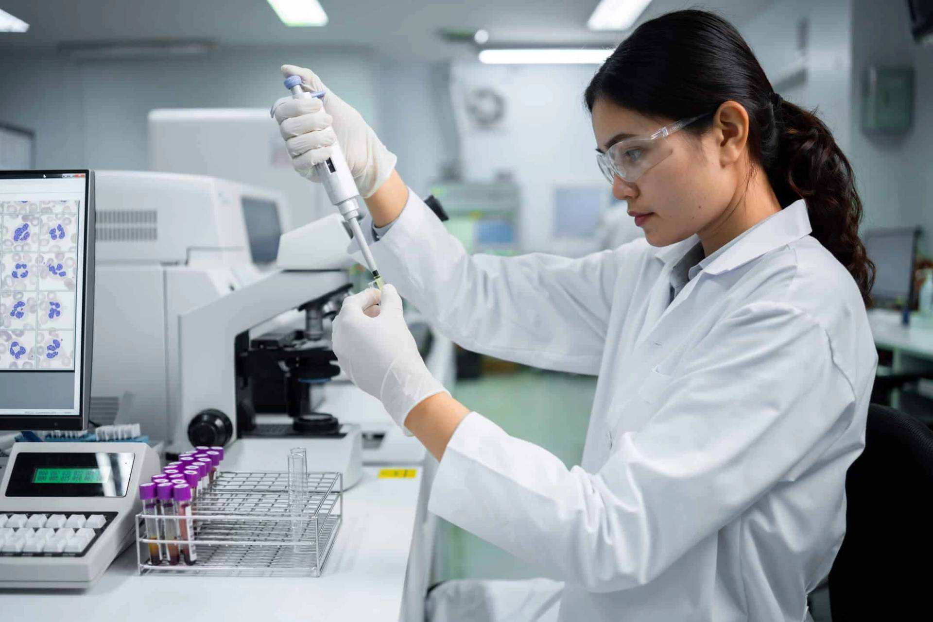 Une personne au laboratoire manipule une pipette et des tubes.