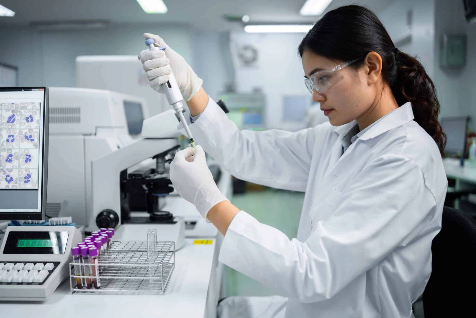 Une personne au laboratoire manipule une pipette et des tubes.
