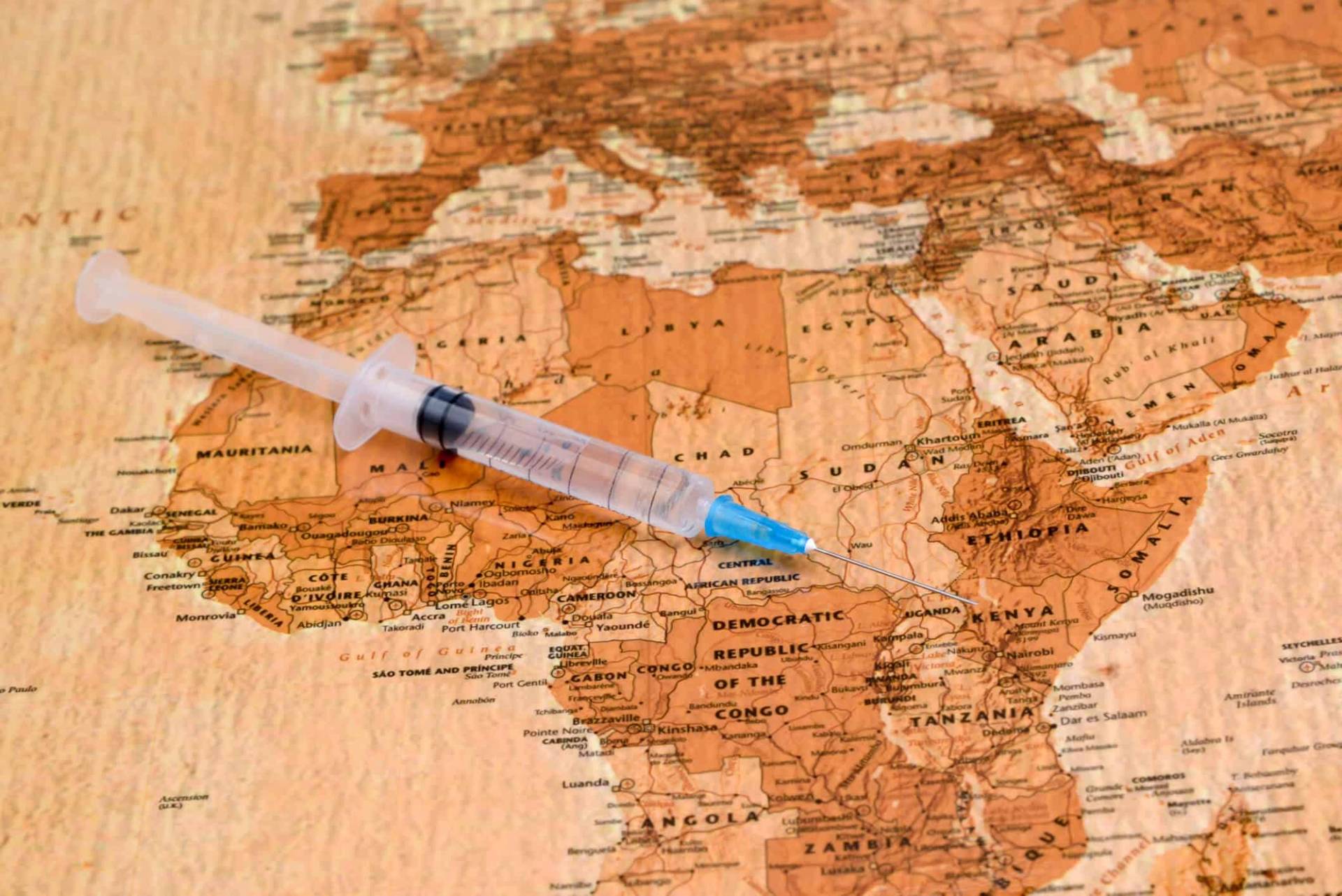 Une seringue est posée sur une carte de l'Afrique.