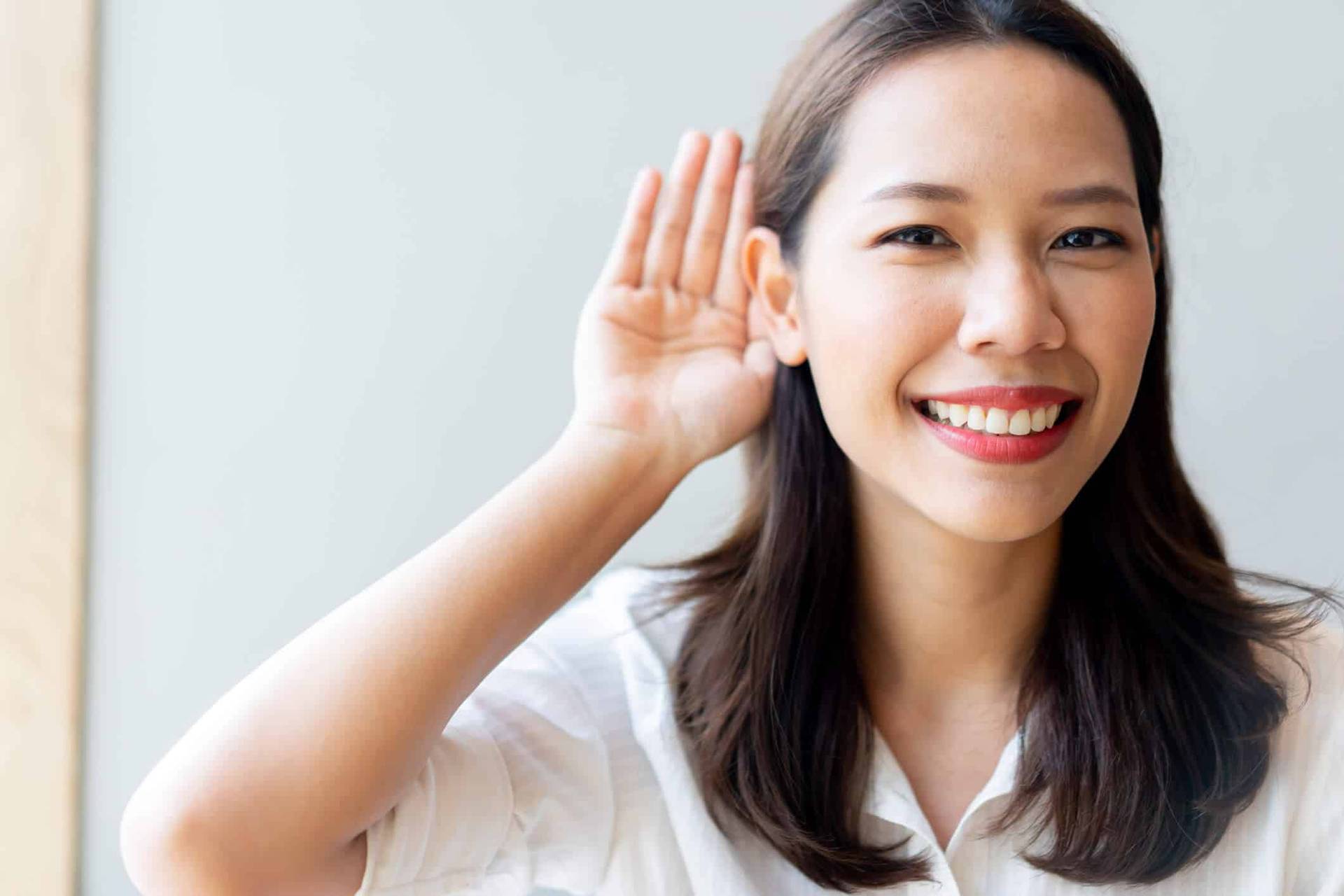 Une femme place la main derrière son oreille.