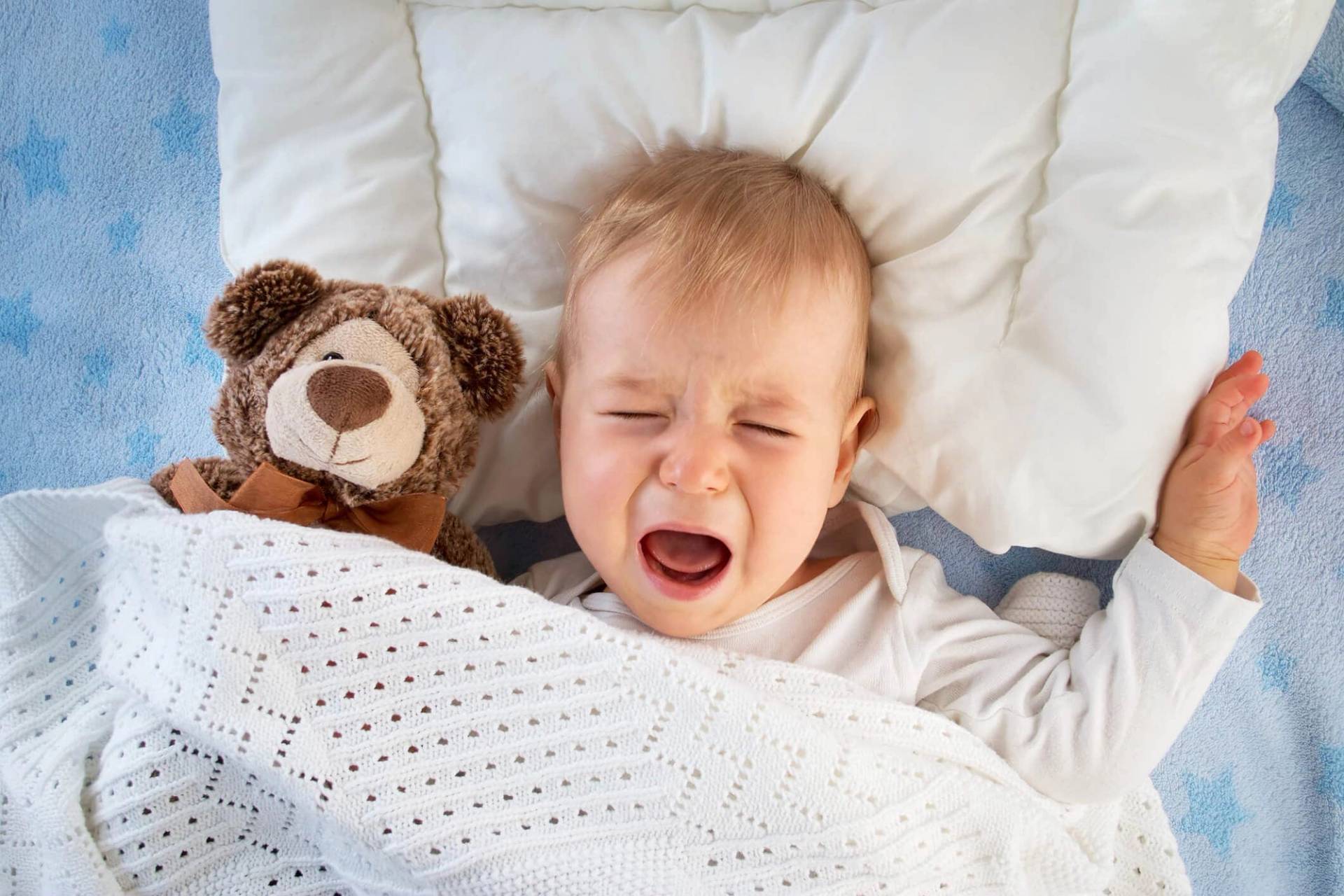 Un bébé allongé dans son lit pleure.