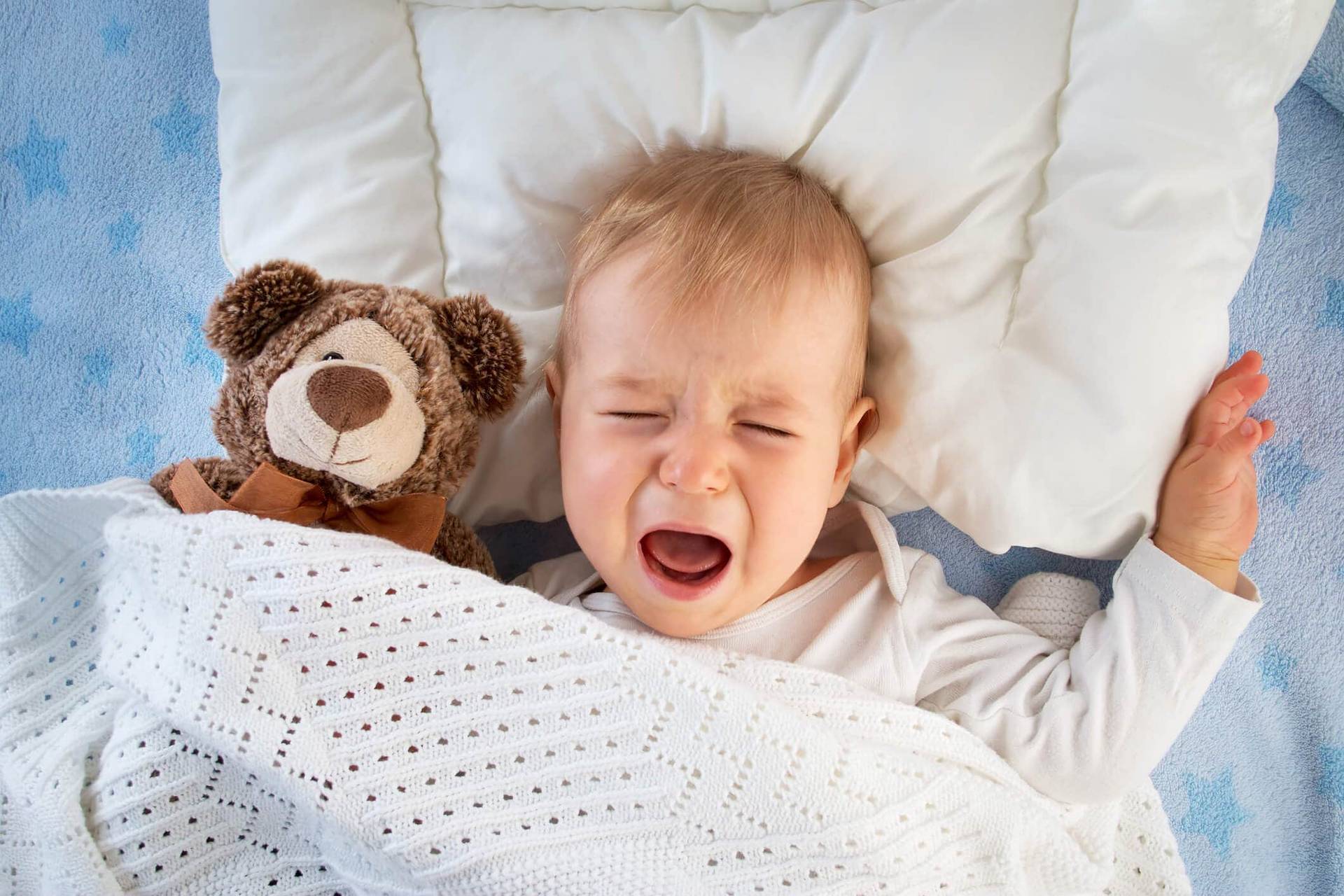 Un bébé allongé dans son lit pleure.