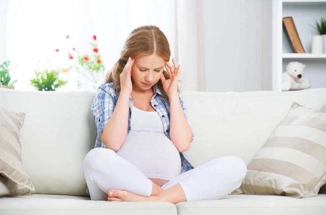 Femme enceinte se tenant la tête durant une consultation médicale pour traiter ses maux de tête