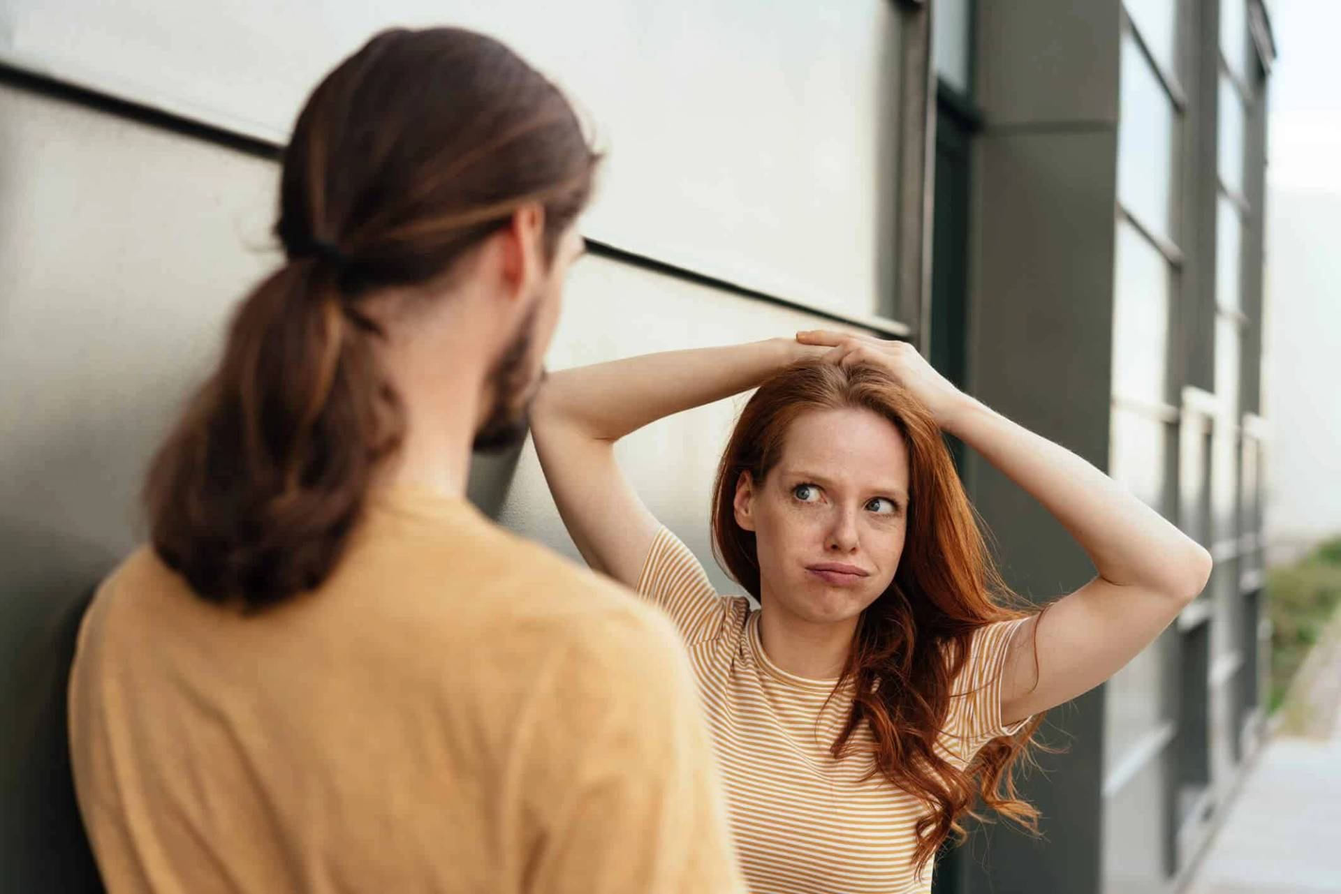 Une femme se regarde dans un miroir, les bras au-dessus de la tête.