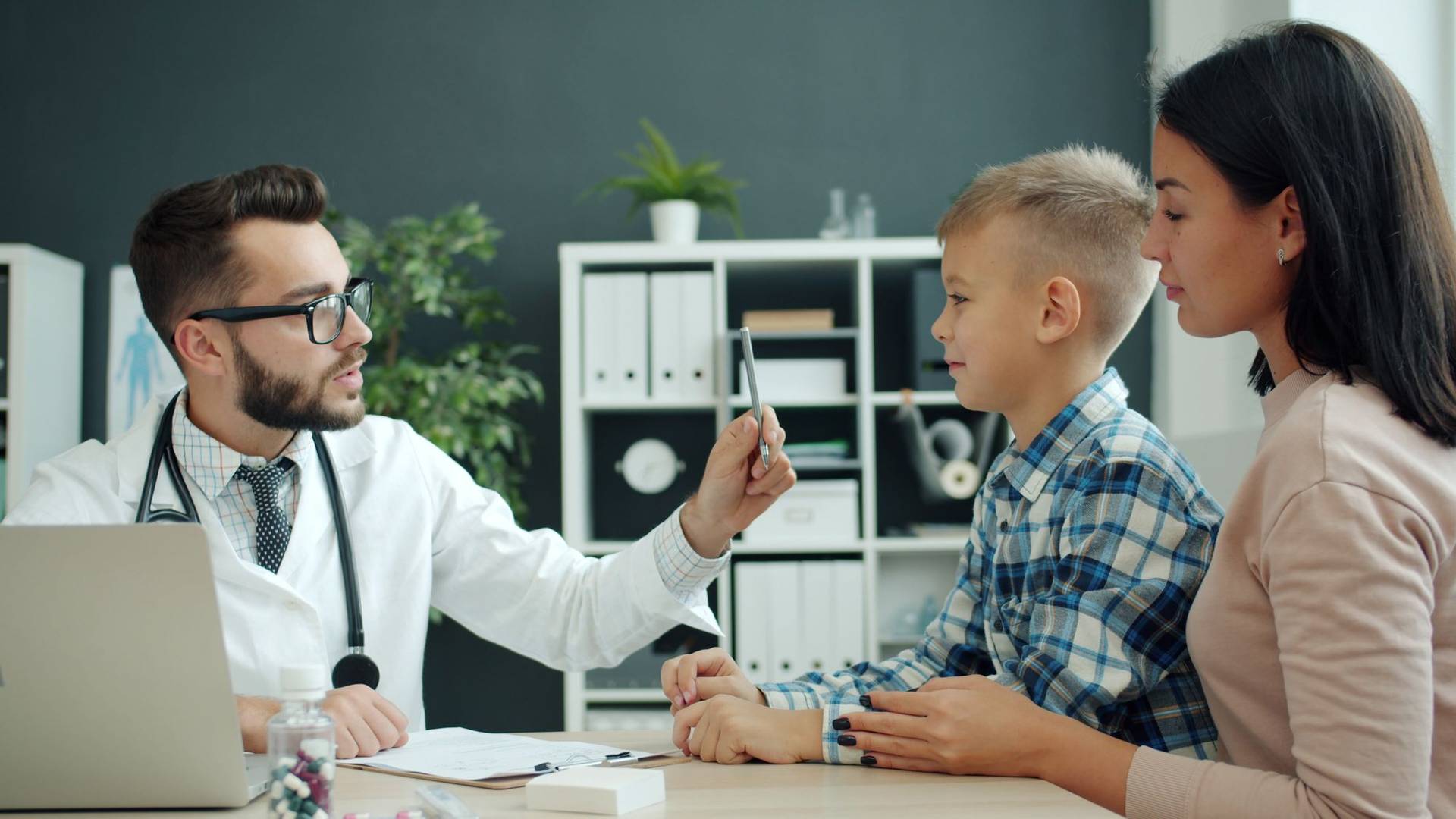 Un médecin explique un diagnostic à une mère et à son fils lors d’une consultation.