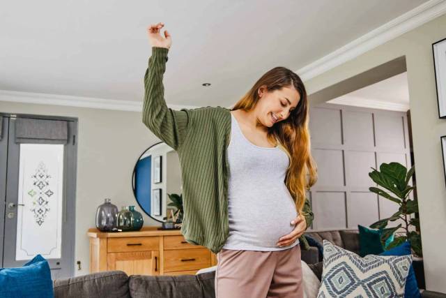 Une femme enceinte s'étire dans son salon.