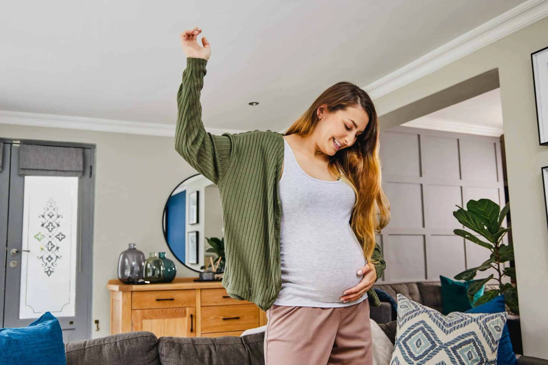 Une femme enceinte s'étire dans son salon.