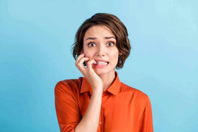 Une femme paraît inquiète, un doigt porté à sa bouche.