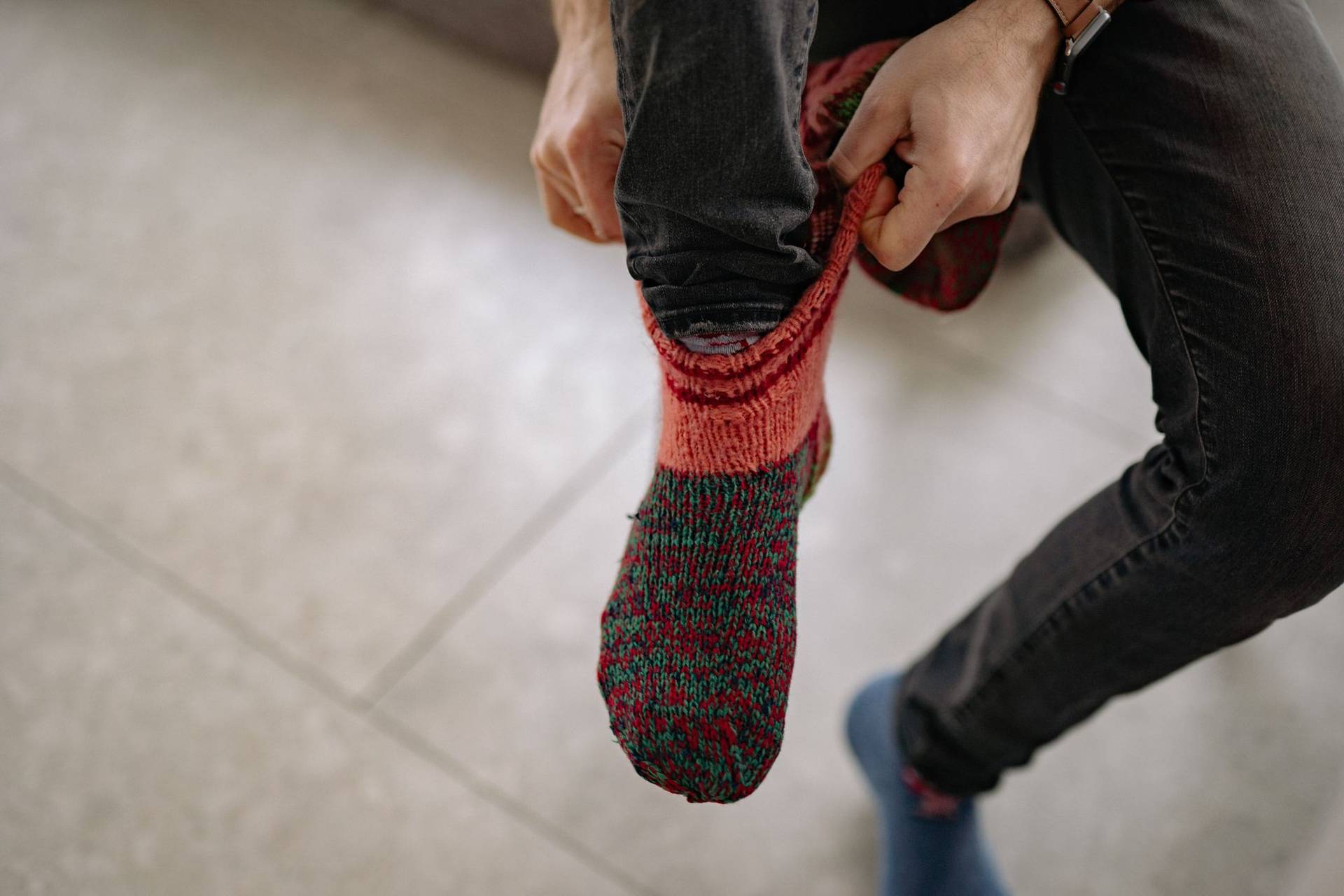 Un homme enfile des chaussettes en laine épaisses, assis à l’intérieur.