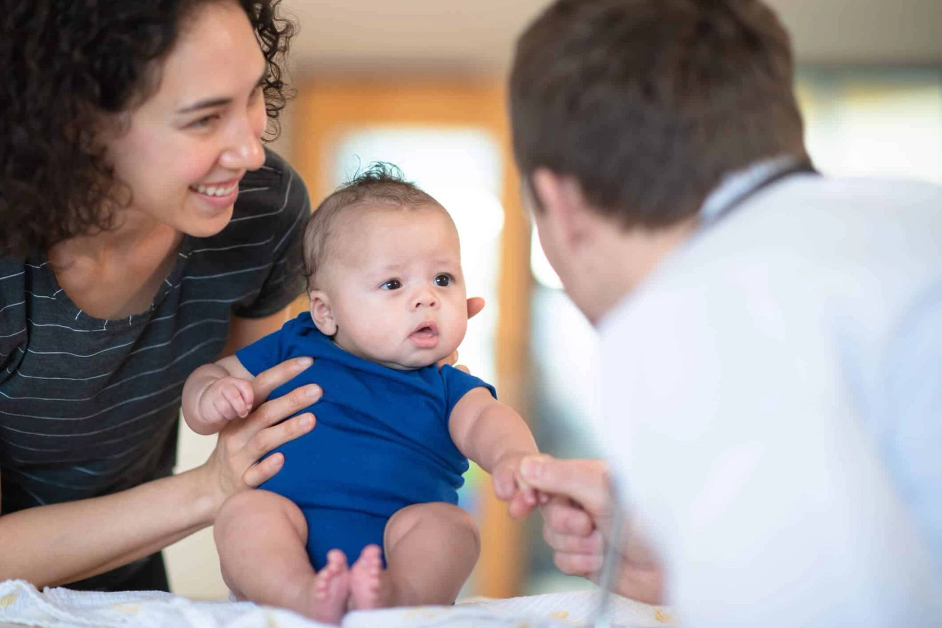 Une mère de famille tenant son bébé lors d'une consultation pour vaccination contre la méningite devant un médecin