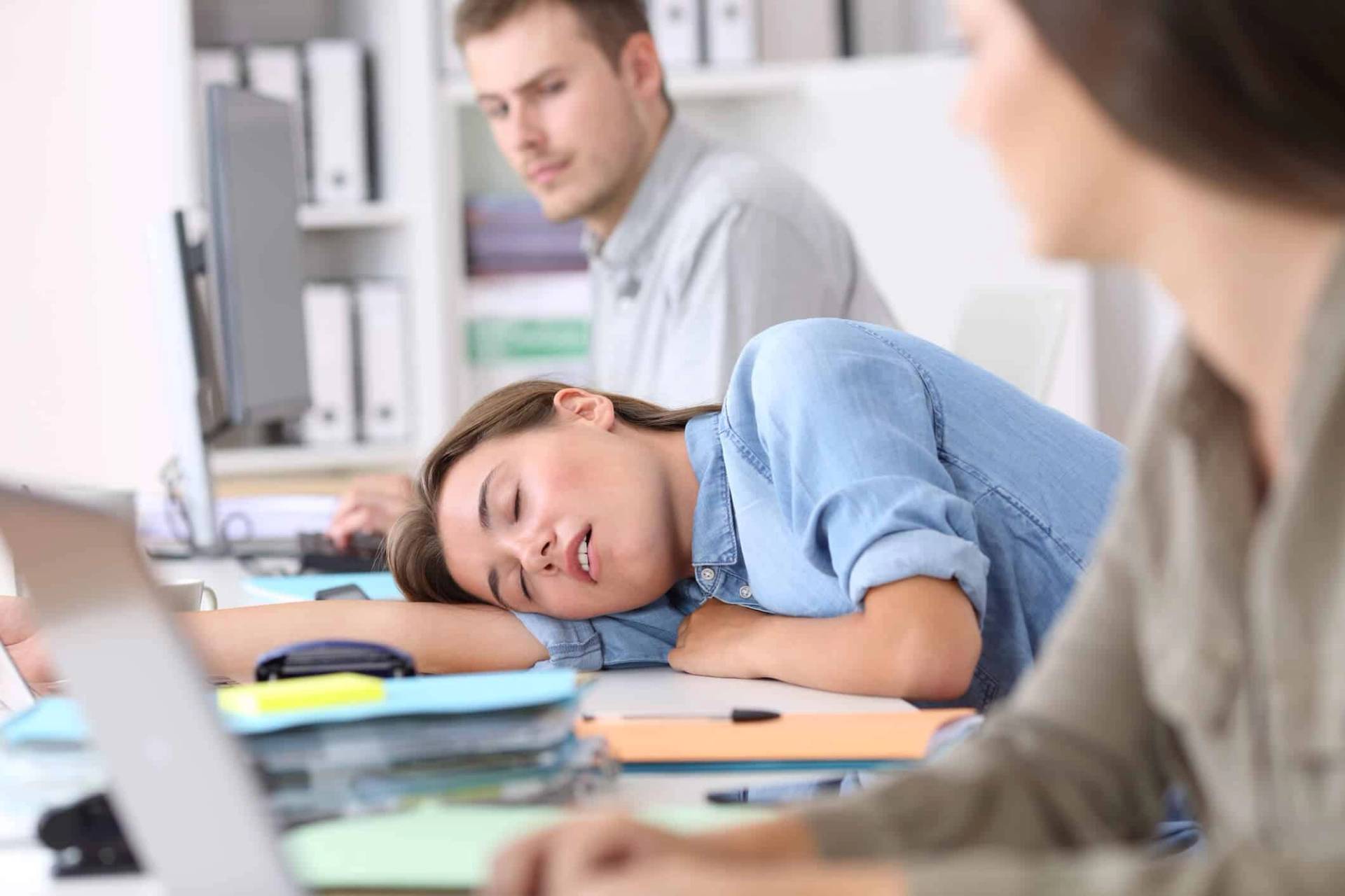 Une personne s'endort la tête posée sur un bureau.