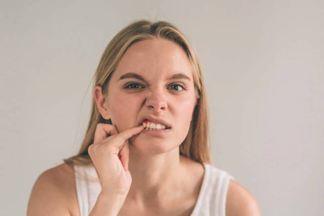 Une femme abaisse sa lèvre pour regarder sa gencive.
