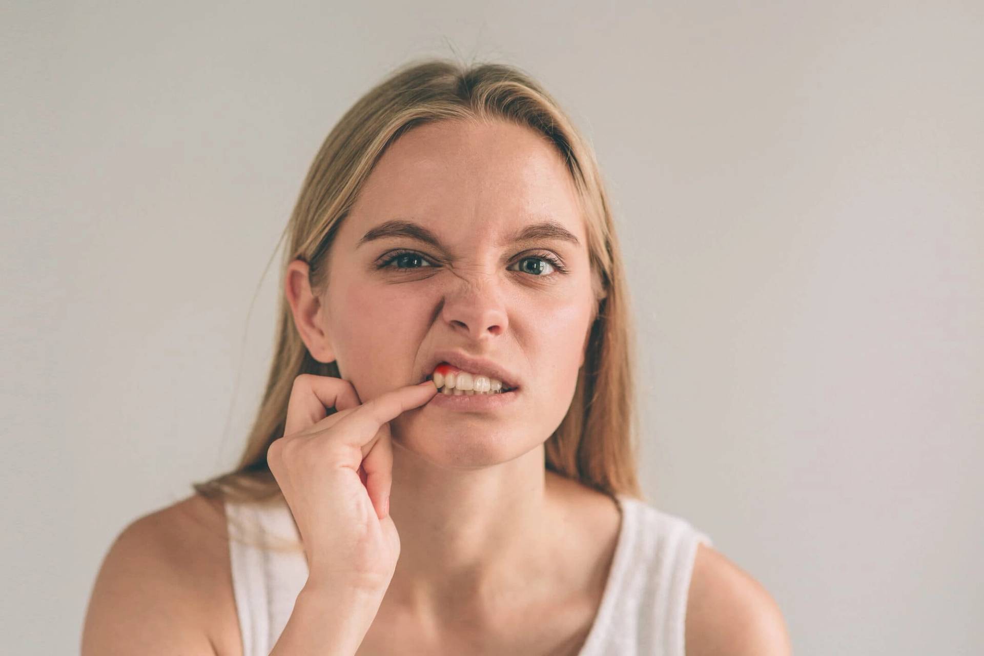 Une femme abaisse sa lèvre pour regarder sa gencive.