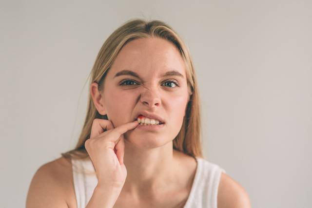 Une femme abaisse sa lèvre pour regarder sa gencive.