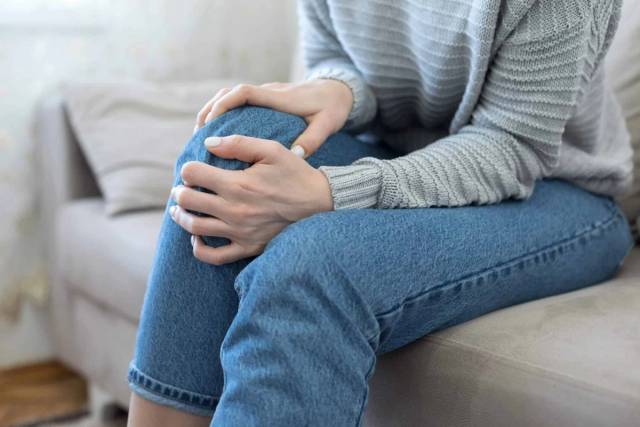 Une personne assise pose les mains sur son genou.