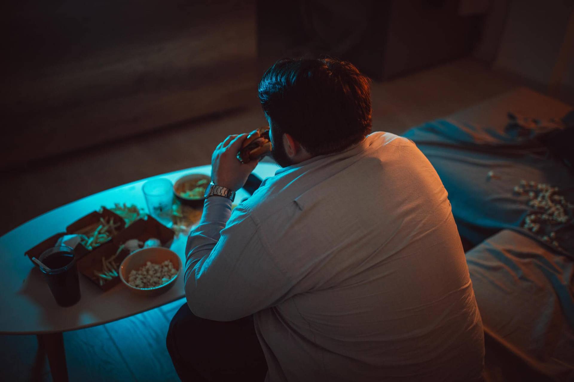 Personne mangeant devant un écran, entourée de plats à emporter.