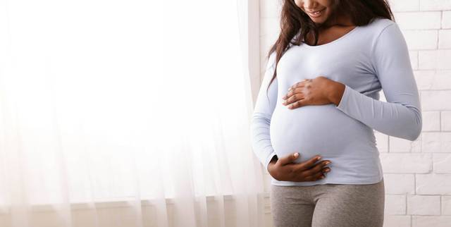 Une femme enceinte pose les mains sur son ventre.