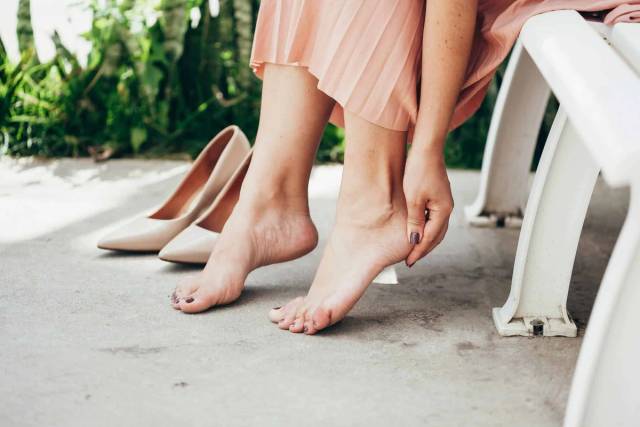Une femme pieds nus touche le dessus de son pied.