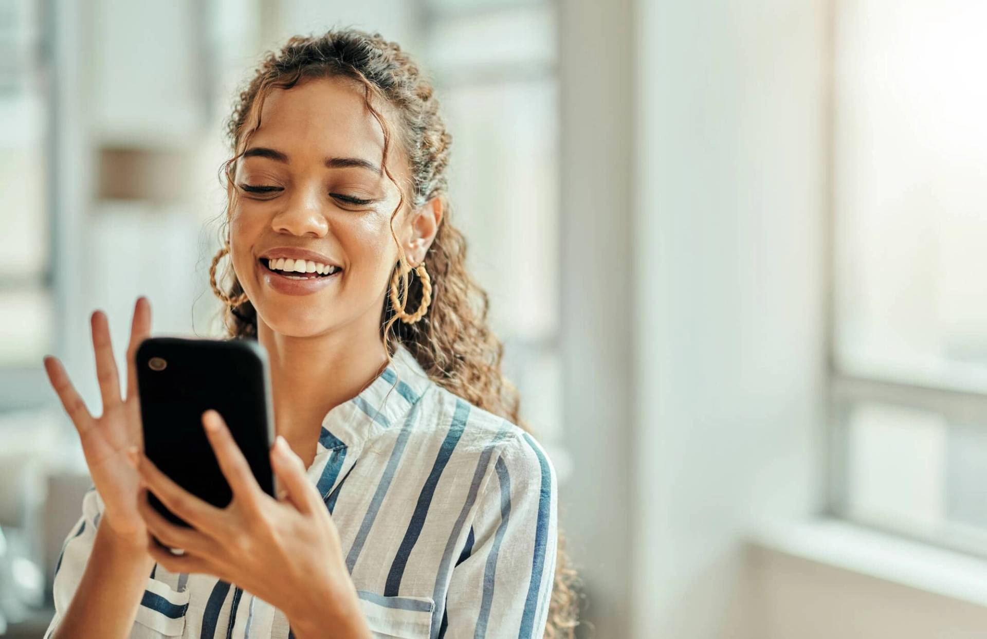 Femme souriante regardant son smartphone.