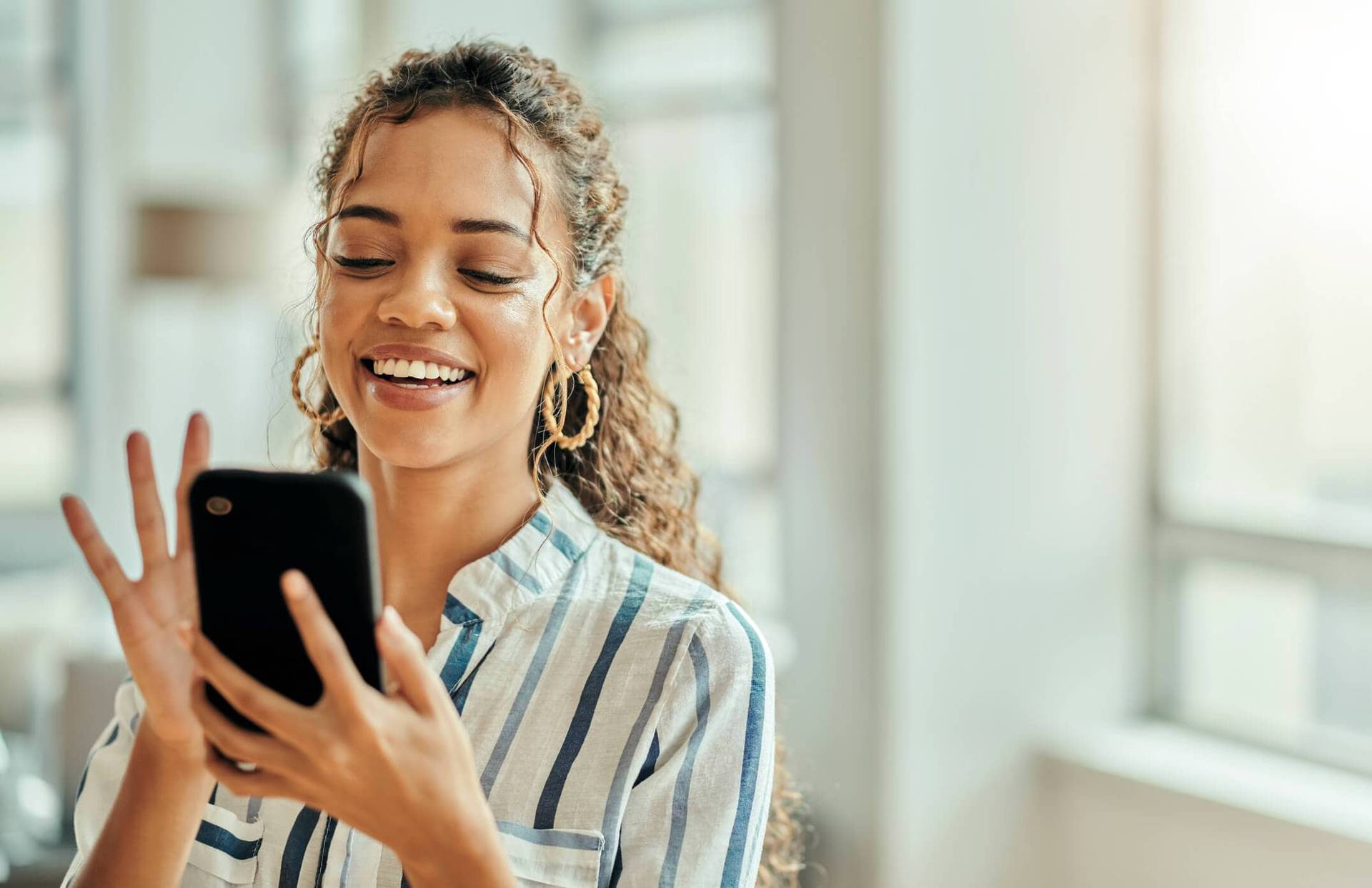Femme souriante regardant son smartphone.