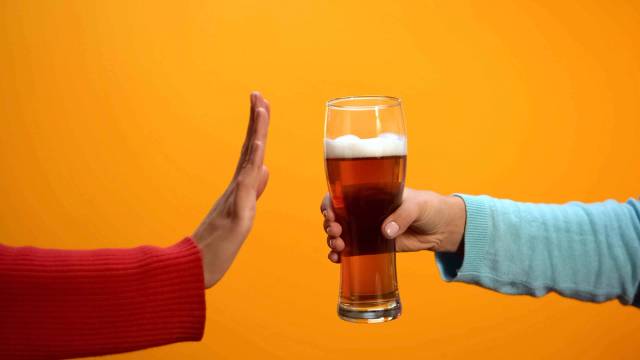Une personne refuse un verre de bière d'un geste de la main.
