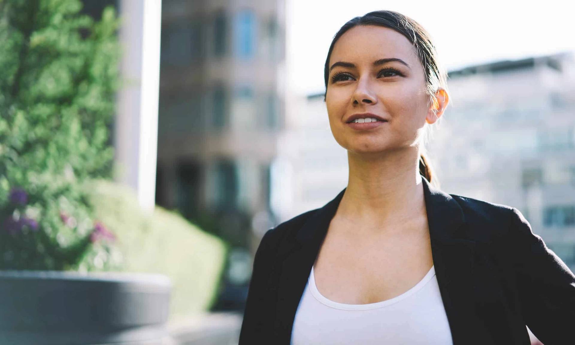 Une femme marche en extérieur, le regard tourné vers le ciel.