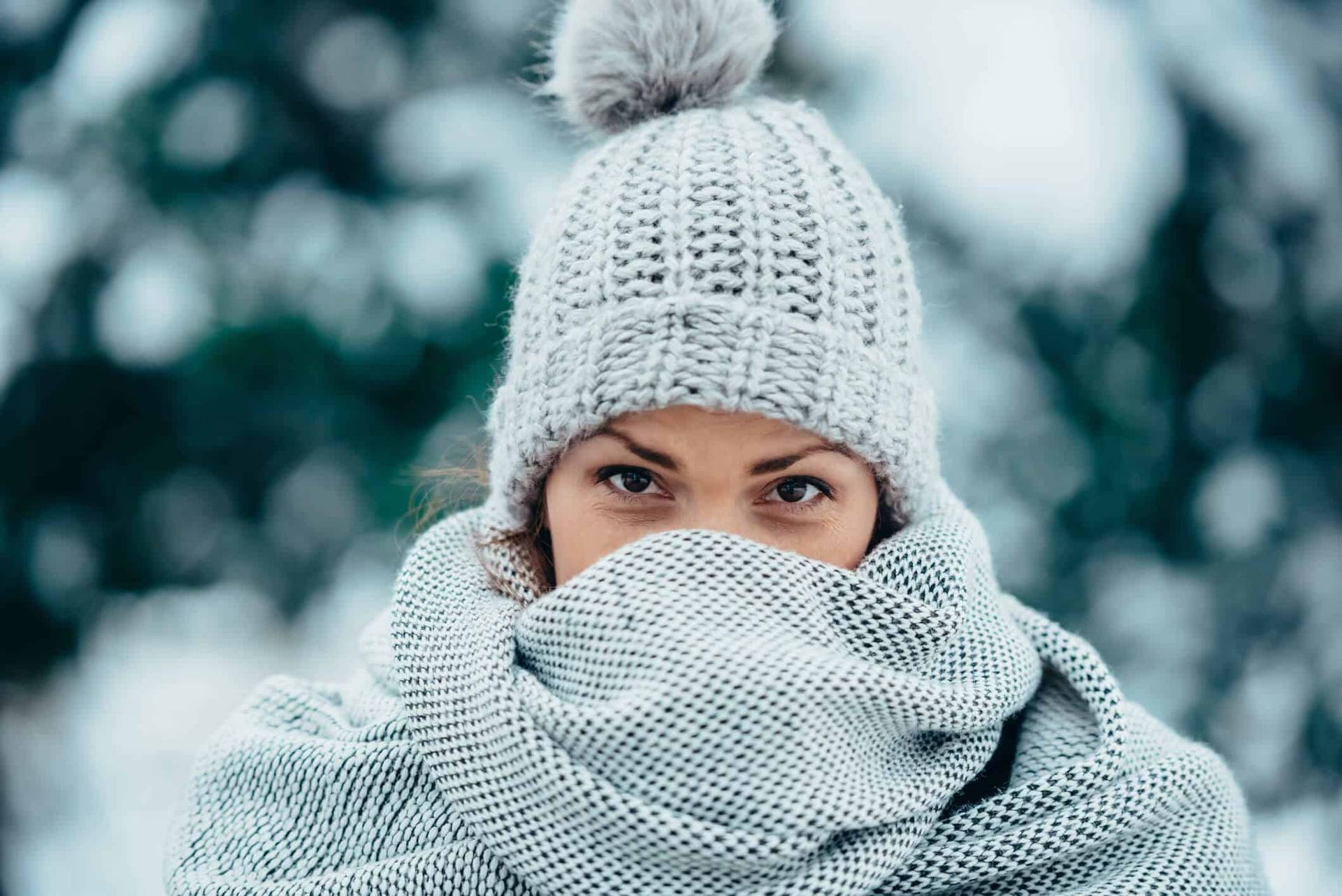 Femme portant un bonnet et une écharpe couvrant son visage.