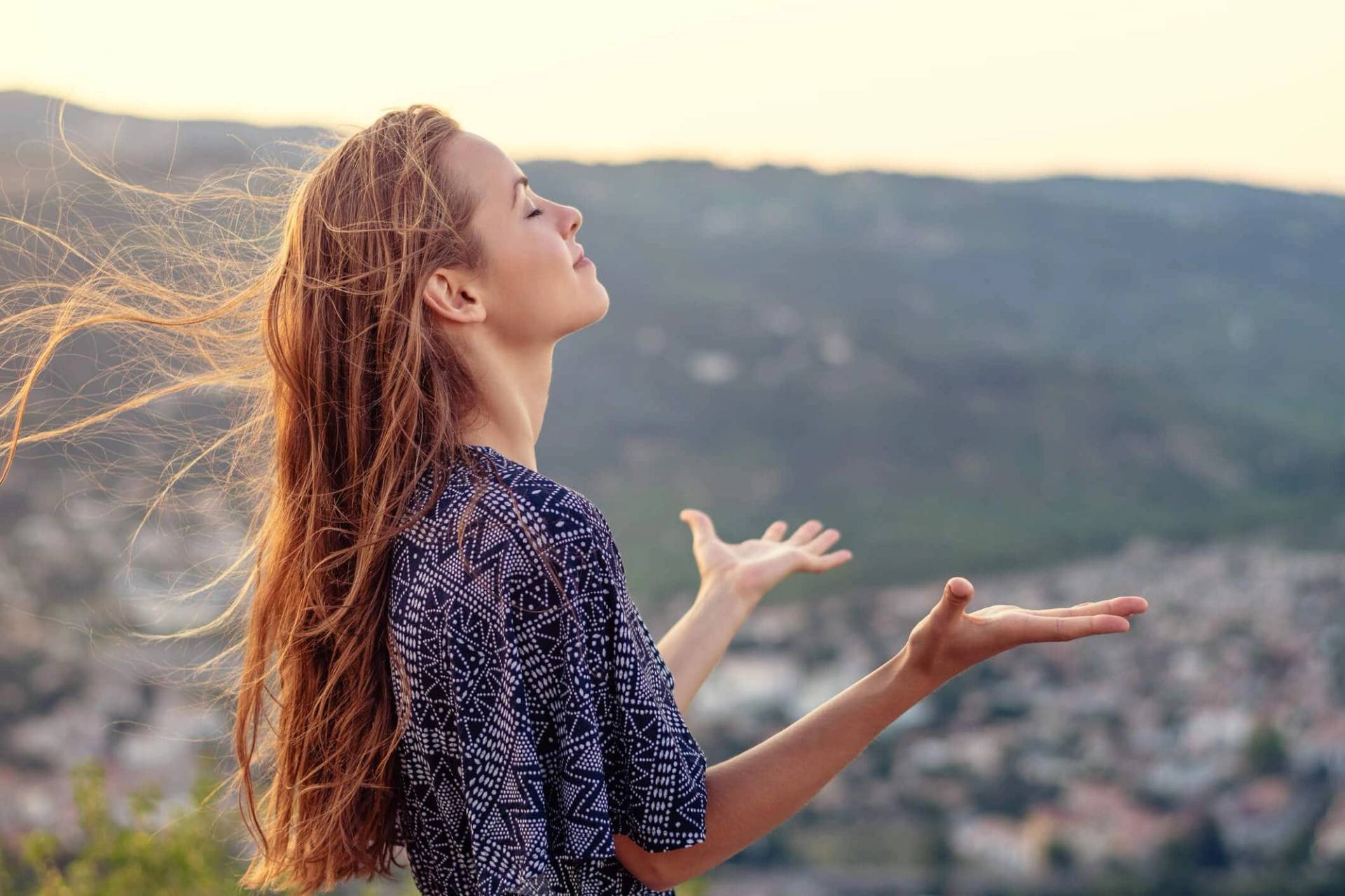 Femme face au soleil dans un paysage extérieur.