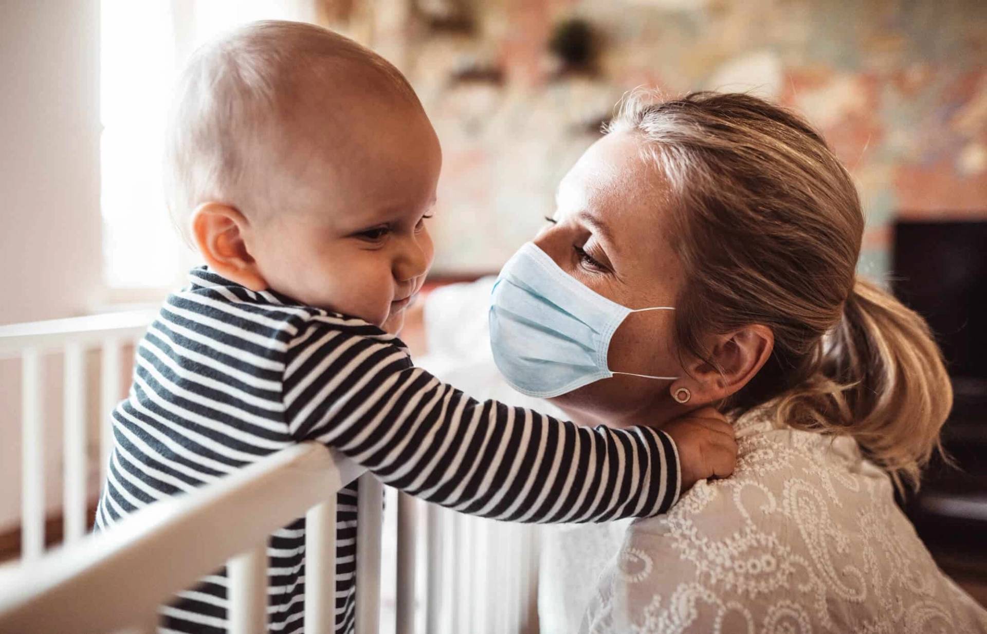Une femme portant un masque tient un bébé dans ses bras.