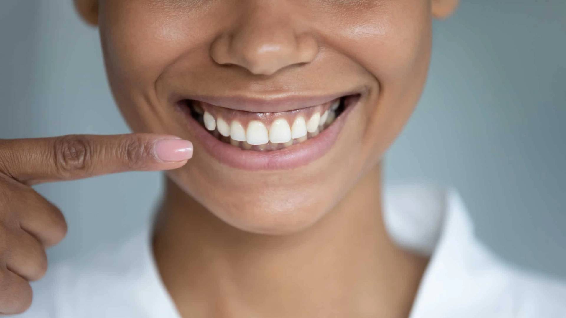 Une personne sourit et montre ses dents avec un doigt.