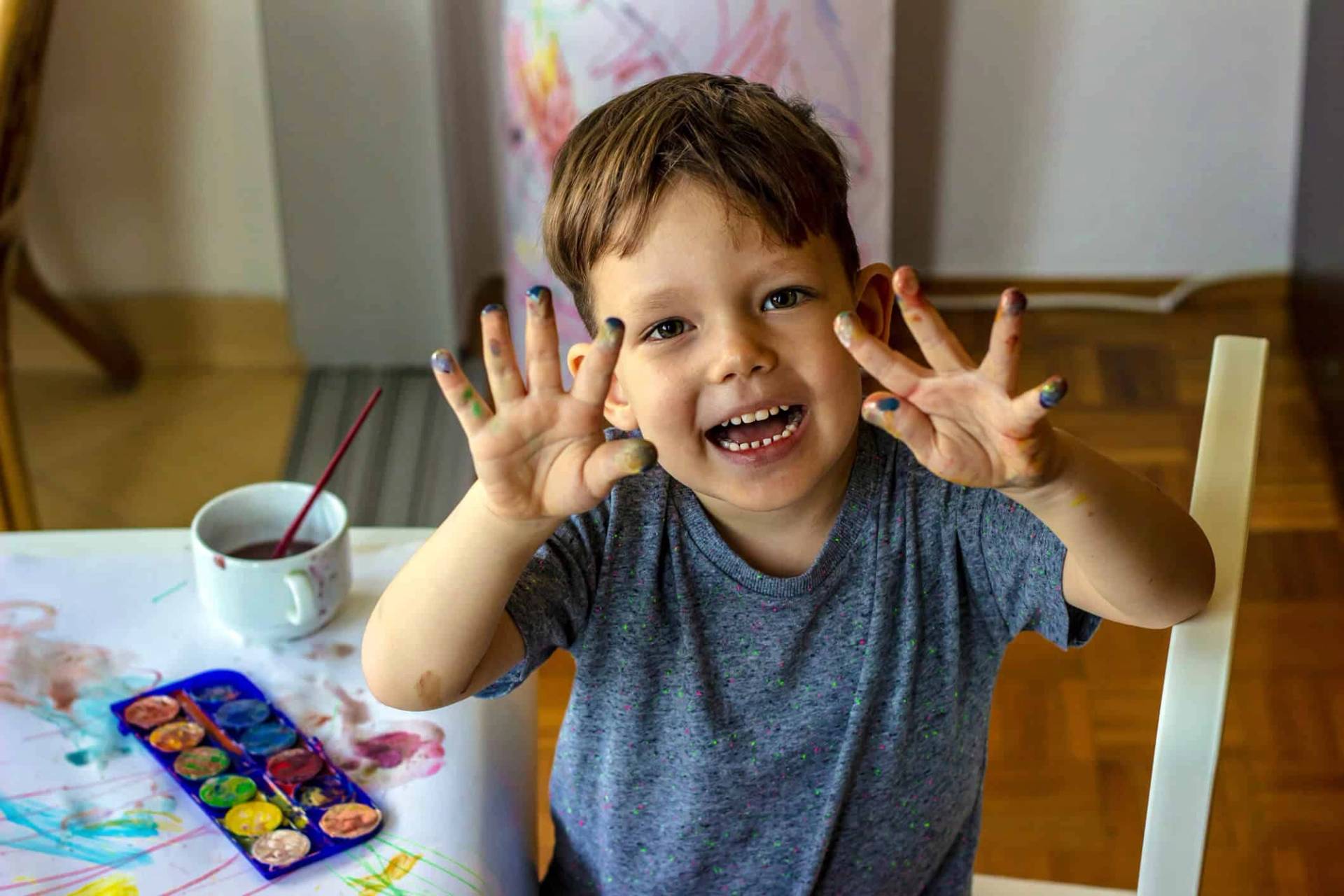 Un enfant montre ses mains couvertes de peinture.