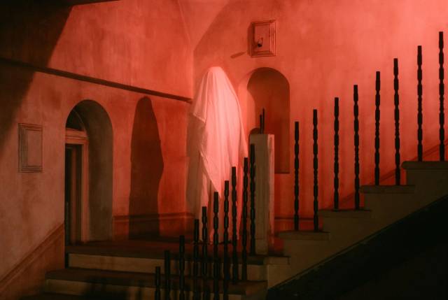 Une scène effrayante avec une mystérieuse figure fantomatique drapée de blanc sur un escalier faiblement éclairé