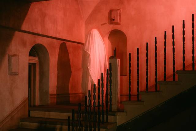 Une scène effrayante avec une mystérieuse figure fantomatique drapée de blanc sur un escalier faiblement éclairé