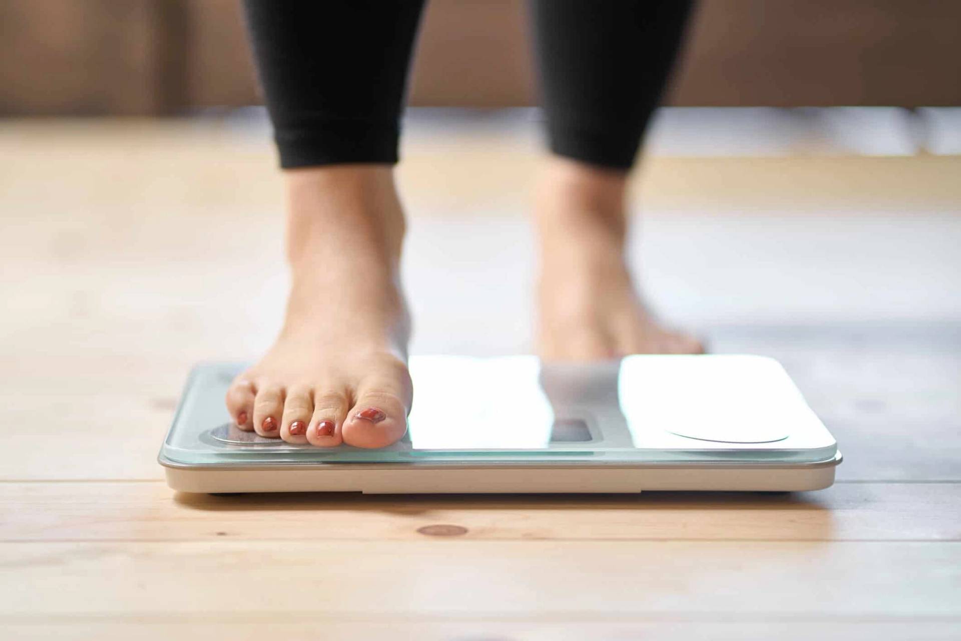Femme qui monte sur une balance pour se peser avec une vue uniquement sur ses pieds