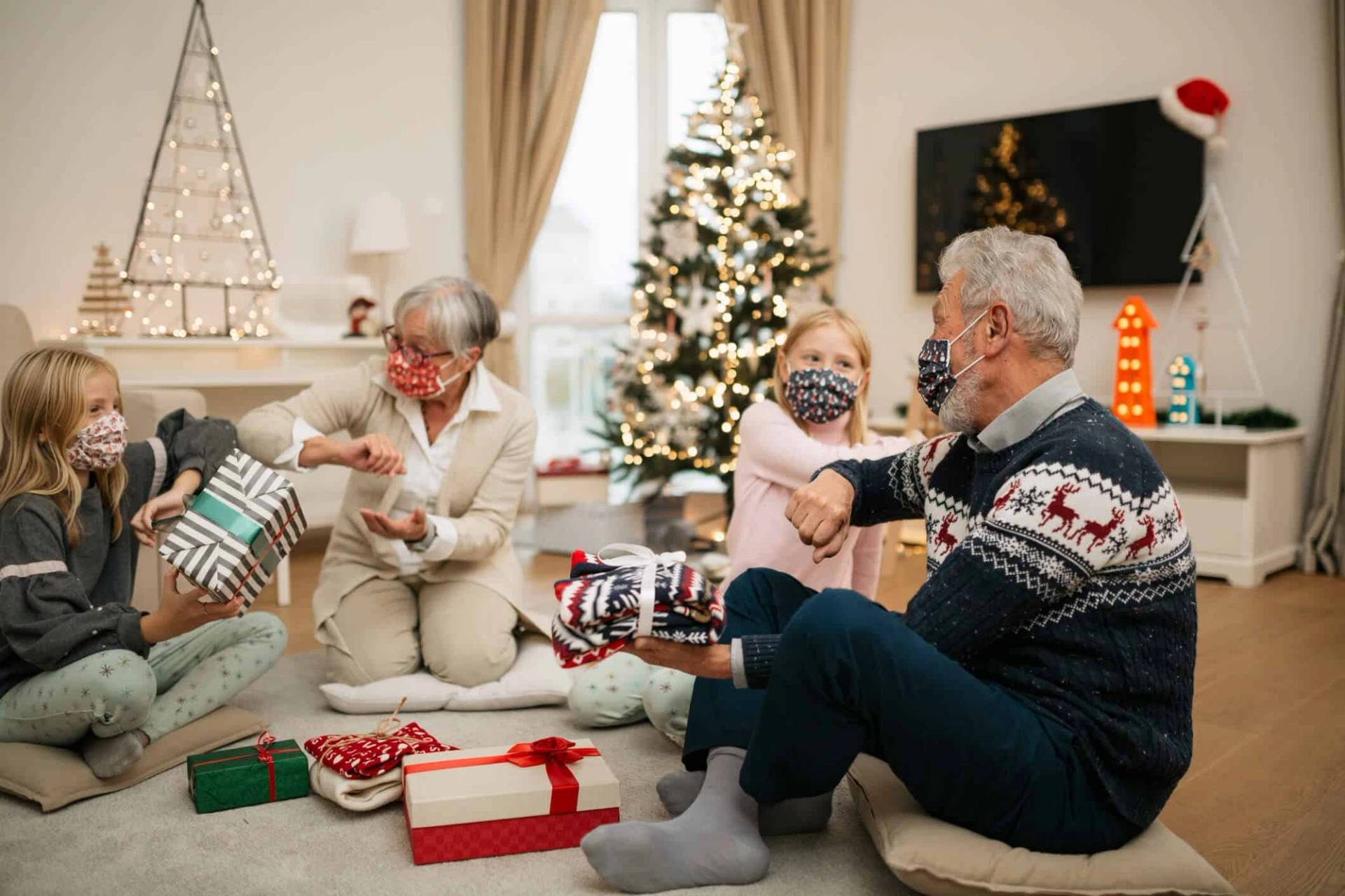 Groupe portant des masques et ouvrant des cadeaux près d’un sapin.