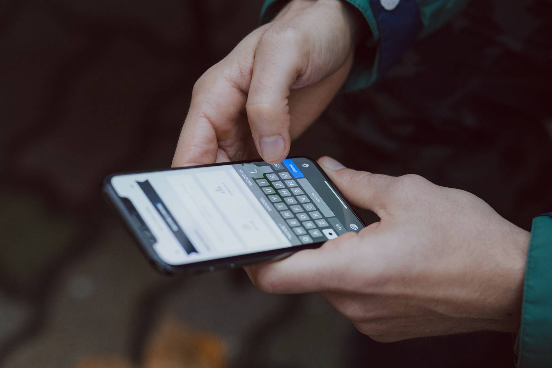 Mains utilisant le clavier d’un téléphone portable.