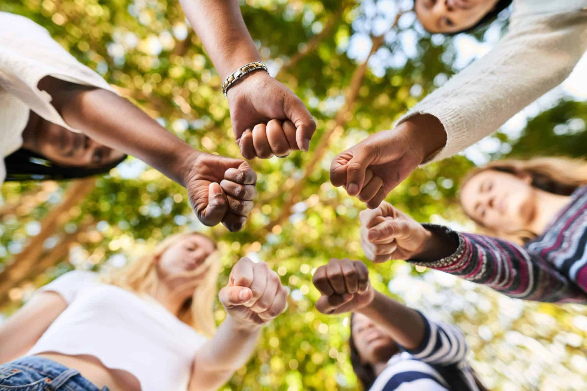 Groupe de personnes réunissant leurs poings en cercle.