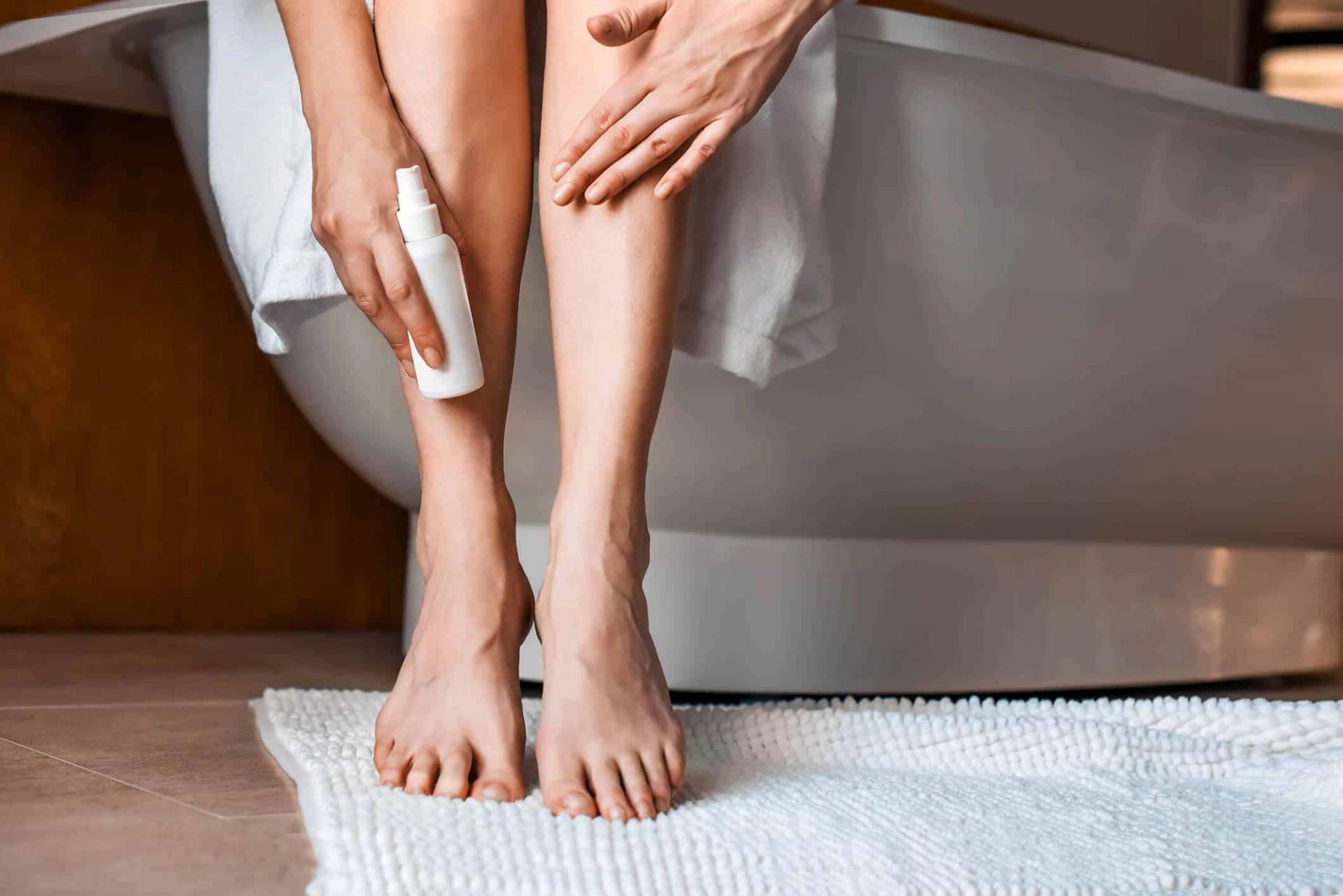 Femme appliquant une lotion sur ses jambes.