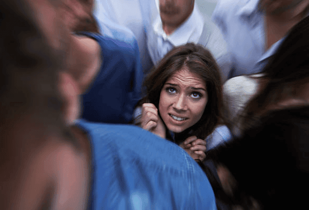 Femme entourée d’une foule serrée, regardant vers le haut.