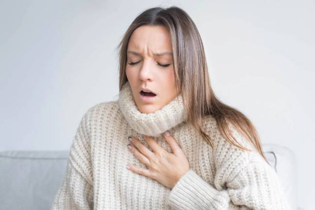 Femme bouche entrouverte, main sur le haut du thorax.
