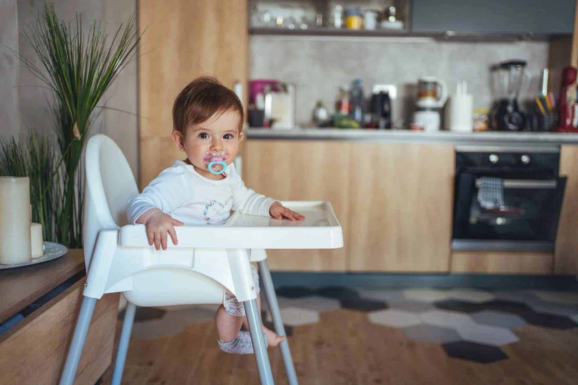 Bébé avec une tétine assis dans une chaise haute.