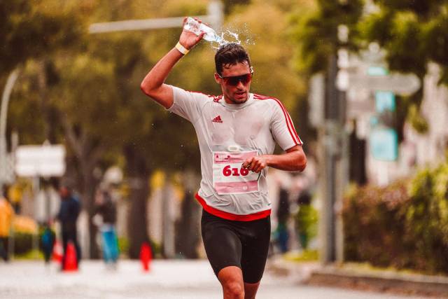 Athlète de marathon versant de l'eau sur sa tête pour se rafraîchir pendant une course intense