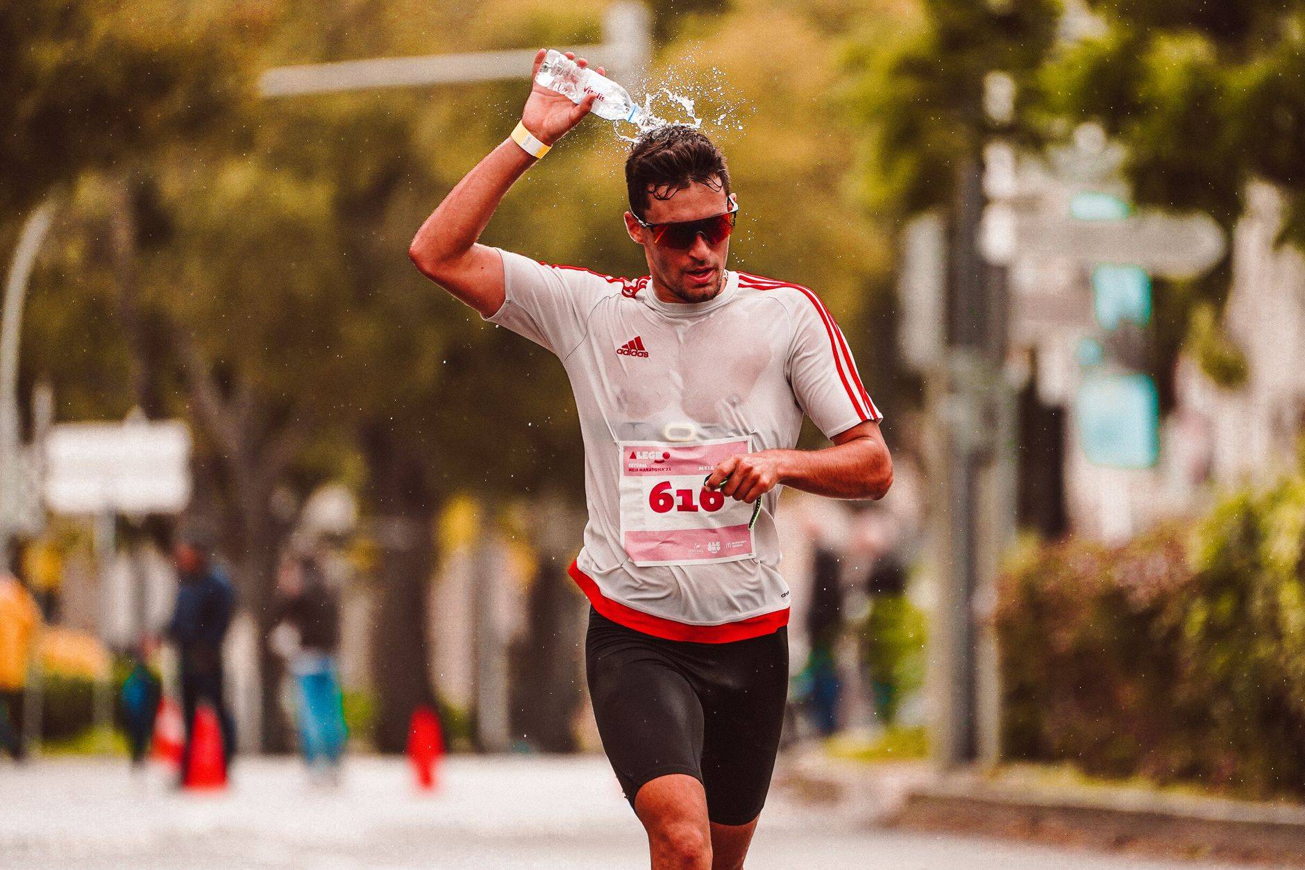 Athlète de marathon versant de l'eau sur sa tête pour se rafraîchir pendant une course intense