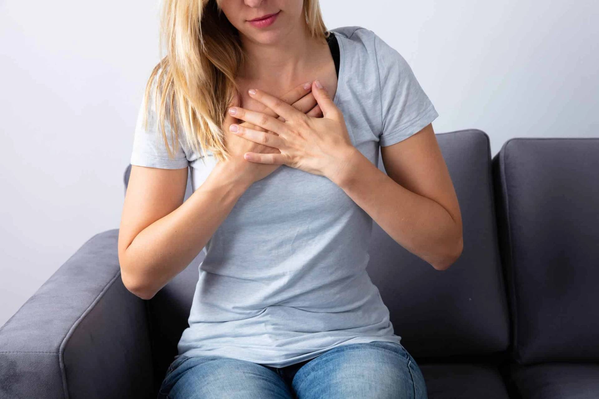 Femme assise portant les deux mains sur la poitrine.