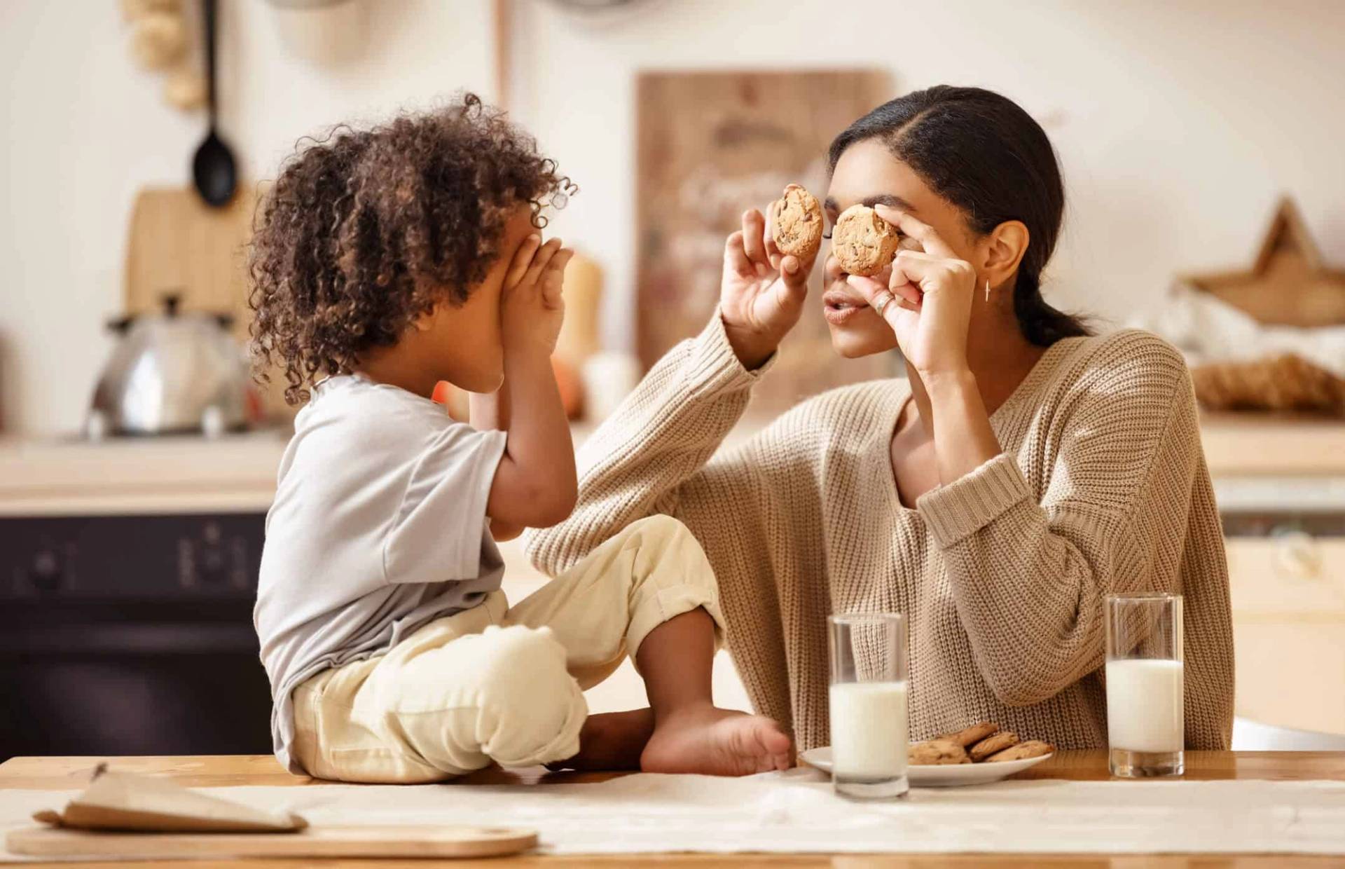 Adulte et enfant jouant avec de la nourriture à une table de cuisine.