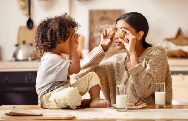 Adulte et enfant jouant avec de la nourriture à une table de cuisine.
