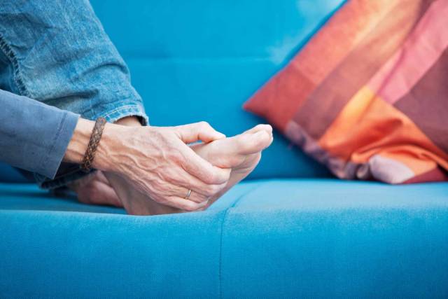 Personne âgée tenant un pied dans ses mains.